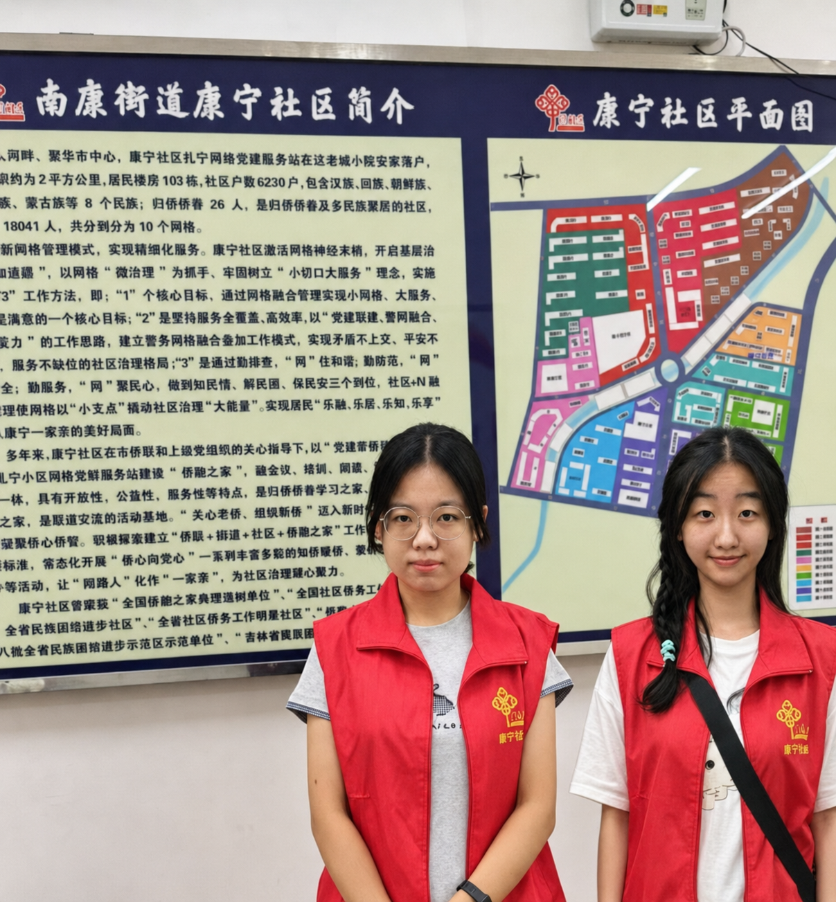 两名实践队成员站在康宁社区简介及社区平面图前